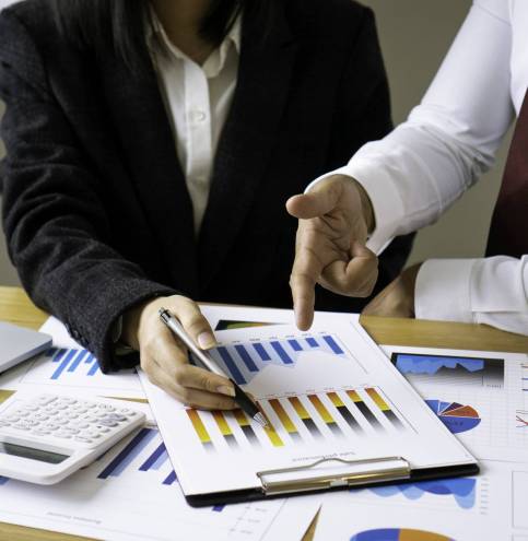 Asian businesswoman or accountant working pointing graph discussion and analysis data charts and graphs and using a calculator to calculate numbers.Business finances and accounting concept